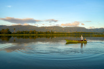 Fisherman in lake against sky