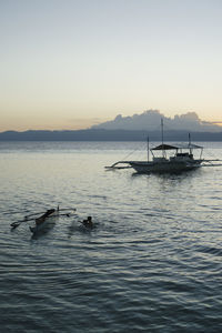 Silhouette boat in sea against clear sky during sunset