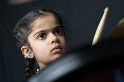 Girl wearing hearing aid while playing drum against wall