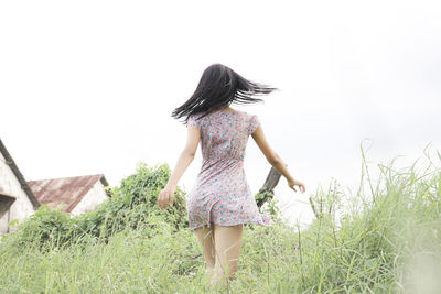 Rear view of young woman dancing around against plants