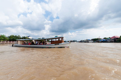 Boat moored in sea against cloudy sky