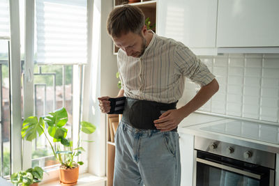 Man wearing back support corset on lower back to treatment of hernia, relieve stress on spine.