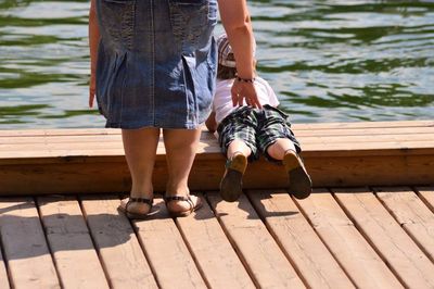 Low section of people standing on pier over lake