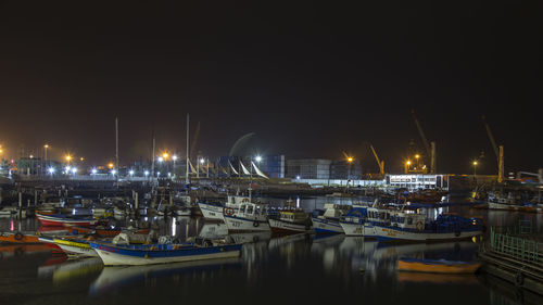 Boats moored at harbor against clear sky at night