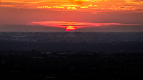 Silhouette cityscape against romantic sky at sunset