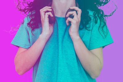 Midsection of woman standing against pink background