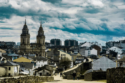 Buildings in city against cloudy sky