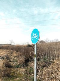 Road sign on field against sky