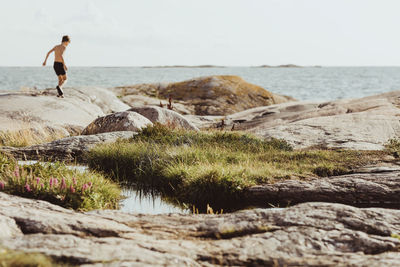 Shirtless boy walking on archipelago during sunny day