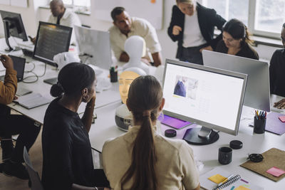 Multiracial female phd students discussing over computer at desk in innovation lab