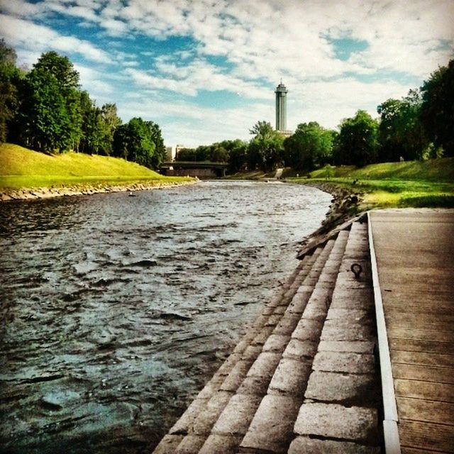 sky, water, tree, the way forward, cloud - sky, built structure, architecture, cloudy, cloud, diminishing perspective, river, nature, building exterior, tranquility, tranquil scene, vanishing point, day, incidental people, footpath, outdoors