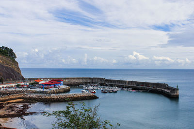 High angle view of boats moored at harbor against cloudy sky