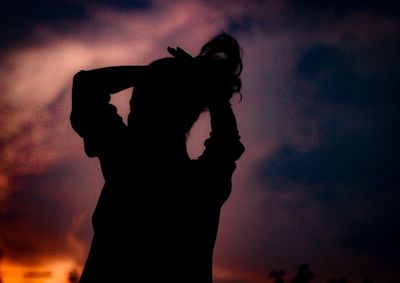 Low angle view of silhouette woman standing against sky during sunset