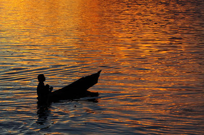 Silhouette person swimming in sea during sunset