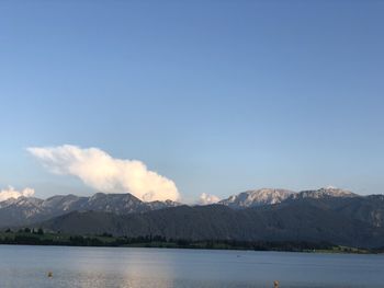 Scenic view of lake and mountains against blue sky