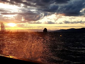 Silhouette man on sea against sky during sunset