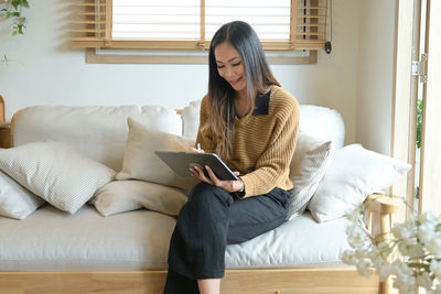 Young woman sitting on sofa at home