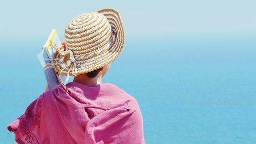 Rear view of woman wearing hat against clear blue sky