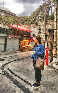 Woman standing with umbrella against building