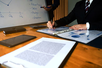 Midsection of businessman with working over graph on table