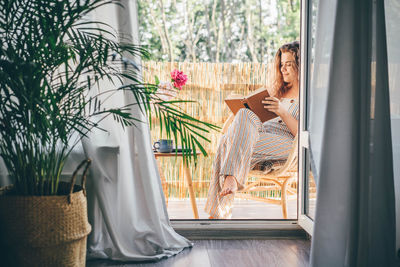 Portrait of woman sitting on window