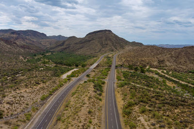 Scenic view of road leading towards mountains against sky