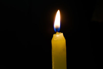 Close-up of lit candle in darkroom