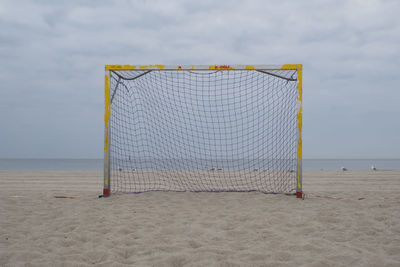 Empty goal on beach against sky