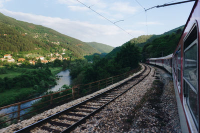 Railroad tracks by mountain against sky