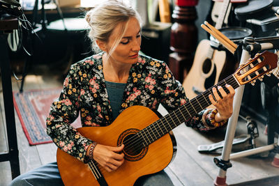 A versatile woman enthusiastically plays the guitar at a music rehearsal.