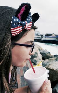 Close-up of girl with tied bow while drinking by sea