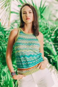 Portrait of young woman standing against plants