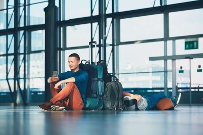 Portrait of smiling young woman sitting on airport window