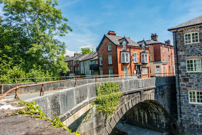 Arch bridge over canal amidst buildings against sky