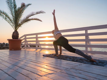 Full length of woman doing yoga on promenade during sunrise