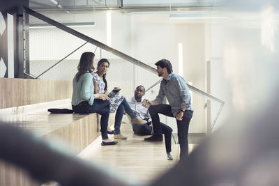 Young business people discussing, sitting on stairs