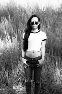 Portrait of young woman wearing sunglasses standing on field