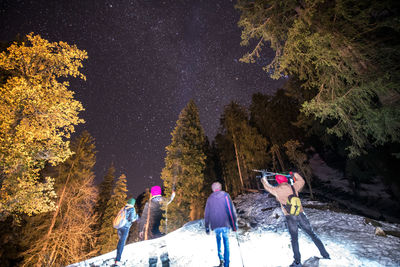 People on snow covered landscape against sky at night