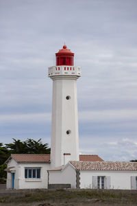 Lighthouse by sea against sky