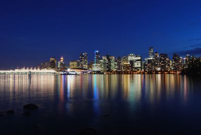 Calm sea with buildings in background at dusk