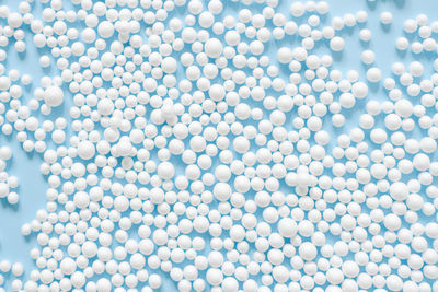 Abstract background consisting of spheres of white color on blue paper top view. minimal arrangement