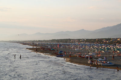People on beach against sky during sunset