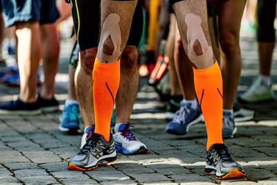 Legs male runner in compression socks and kinesio tape on his knees