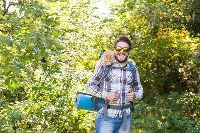 Man with arms outstretched standing against plants