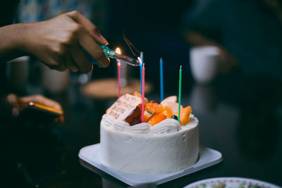 Close-up of hand lighting birthday candles