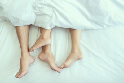 Low section of woman relaxing on bed