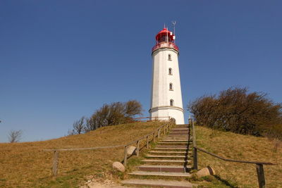 Lighthouse by building against clear sky