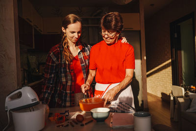 Mother and daughter preparing food at kitchen