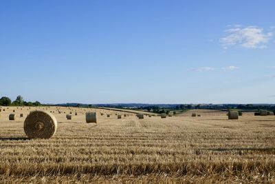 Hay bales on field against sky