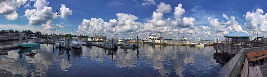 Boats in harbor against cloudy sky